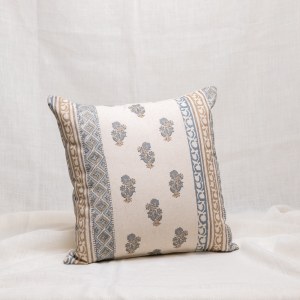Funda de cojín color natural con dibujo de cenefas y flores en tonos azules y beige.