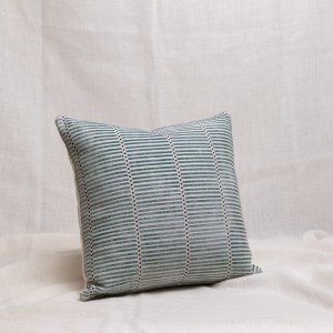 Cojín de rayas tejidas en color verde agua sobre fondo natural