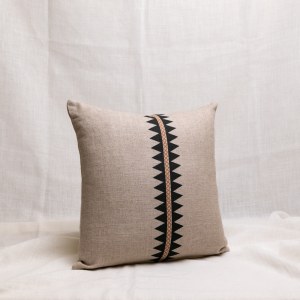 Cojín de lino color natural con una línea en el centro con dibujo geométrico en negro