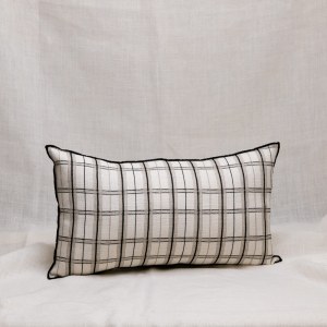 Funda de cojín de lino blanco con dibujo de cuadros en negro y beige, con ribete bordado con hilo negro.